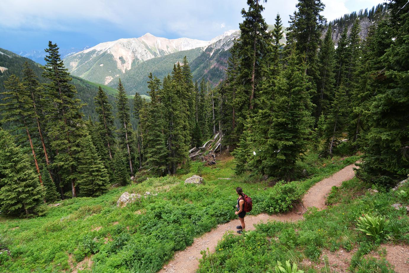 A hiker ascending a trail toward Ice Lake Basin in the San Juan high country